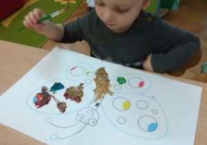 Chłopiec maluje farbami na dużej powierzchni.